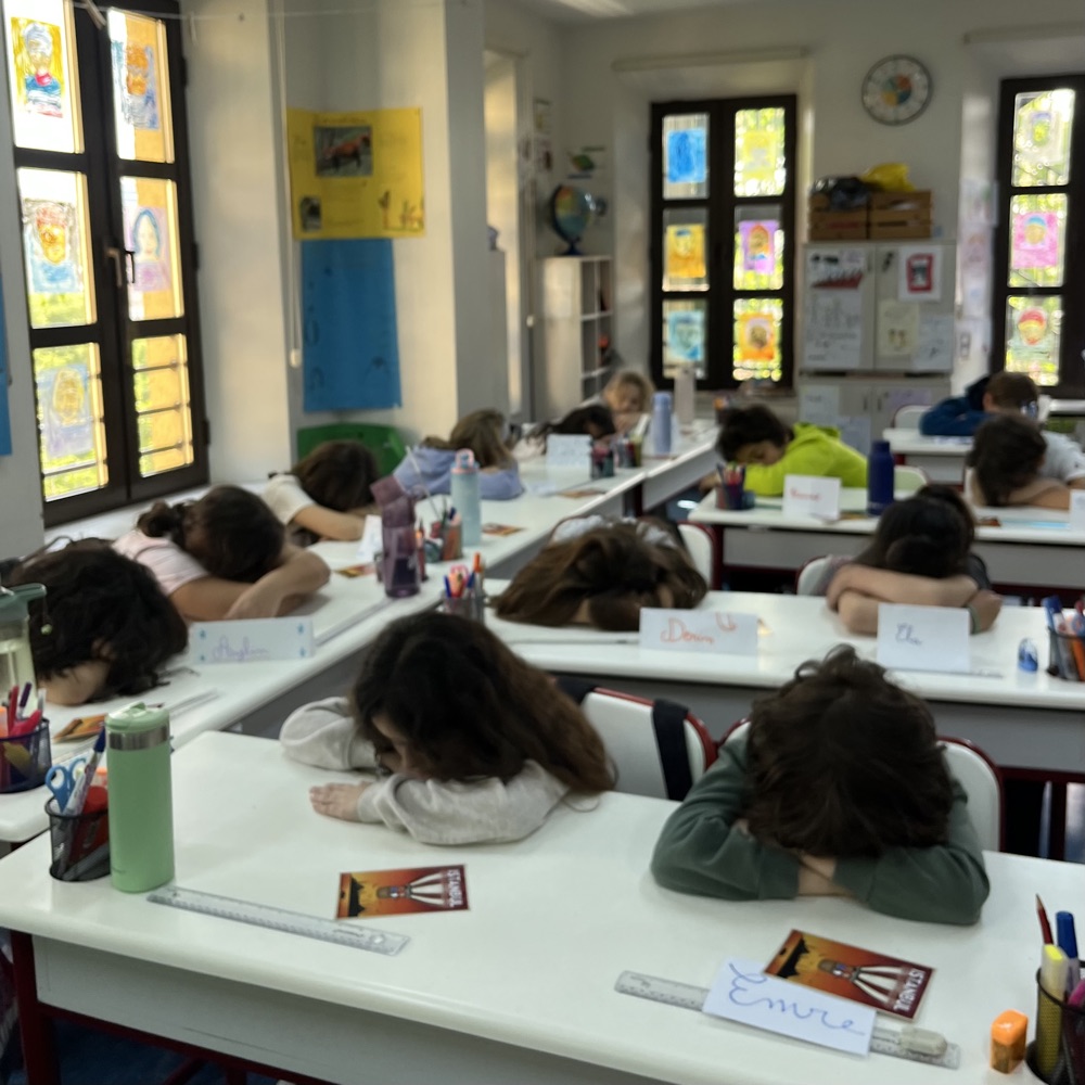 Une classe entière en méditation, têtes posées sur les bras croisés